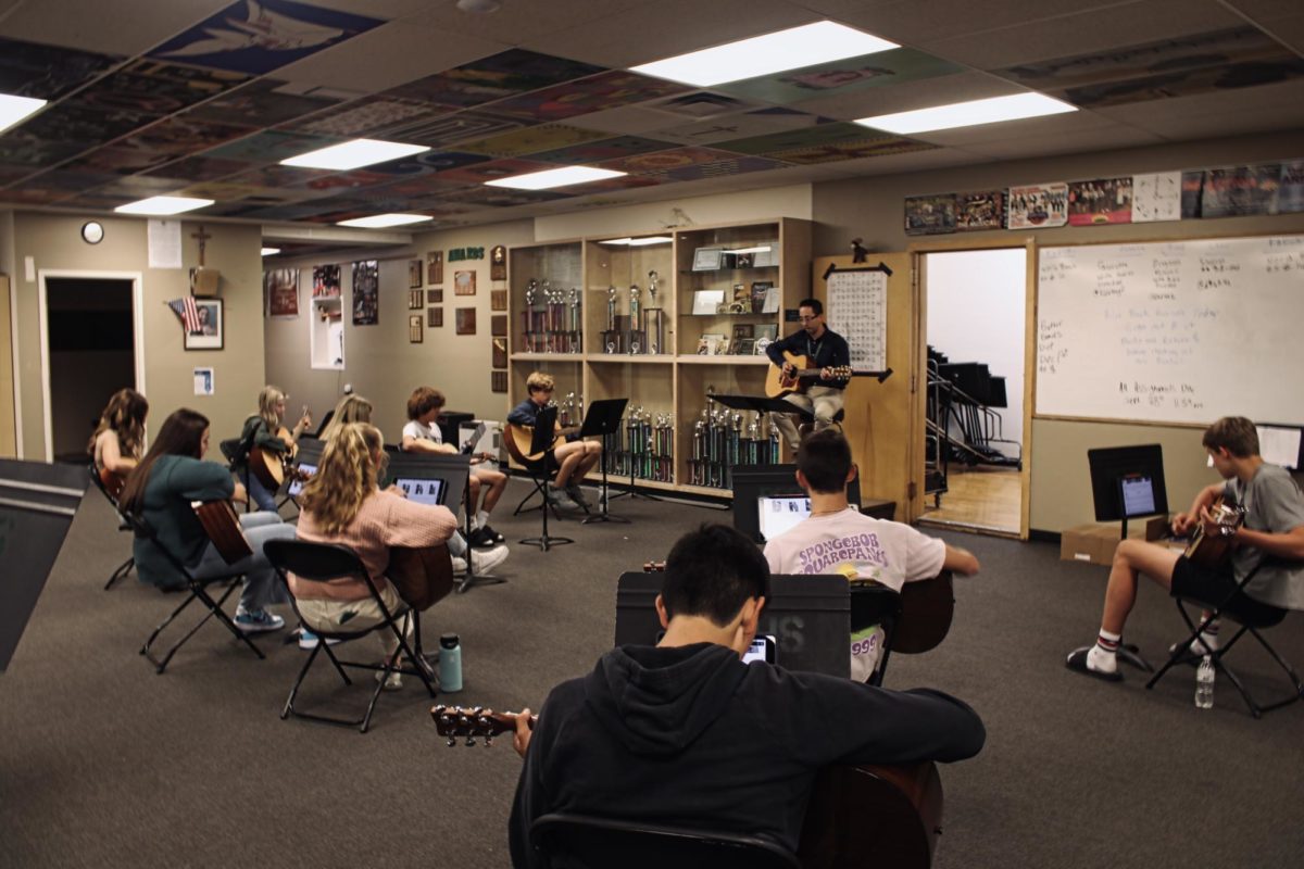 Branden Martinez guides students in learning the guitar for the class, Fundamentals of Art. 