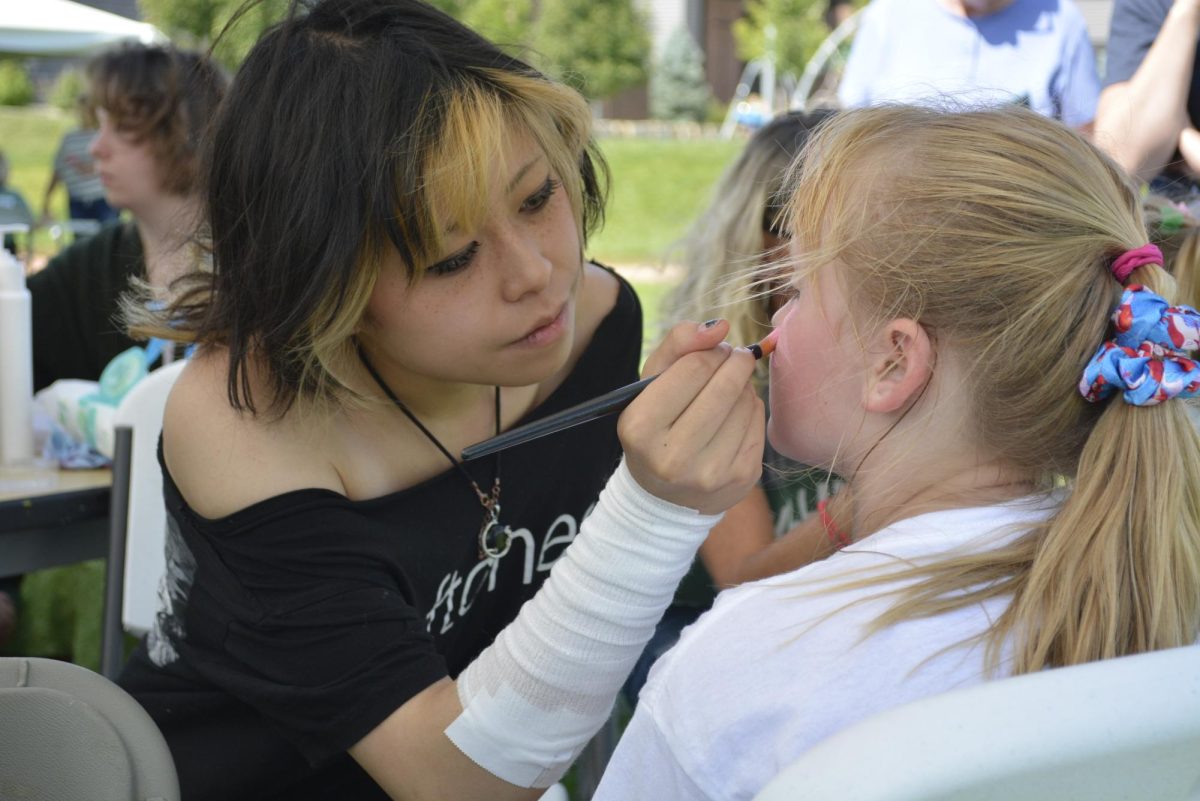 Tia Schosser face painting a SFC student at Running On Faith.