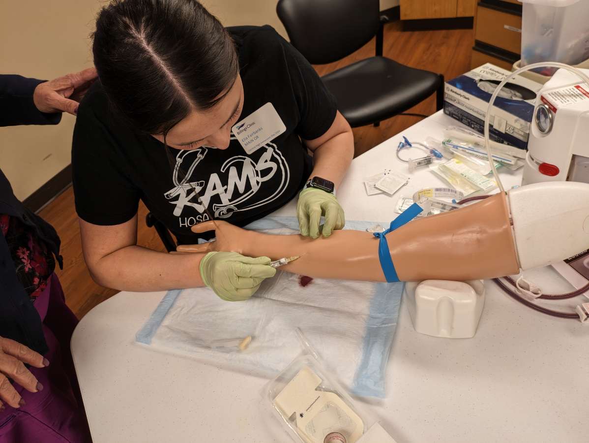 3/27/2024 Sophomore, Ella Fairbanks practicing IV injections at HOSA Immersion Day. 