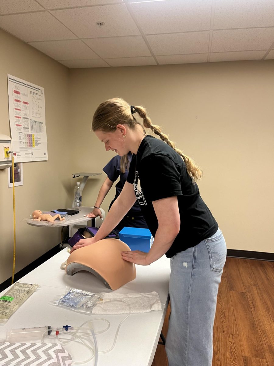 3/27/2024 Junior, Annie Hanser investigating the placement of a baby in a SIM lab mannequin. 