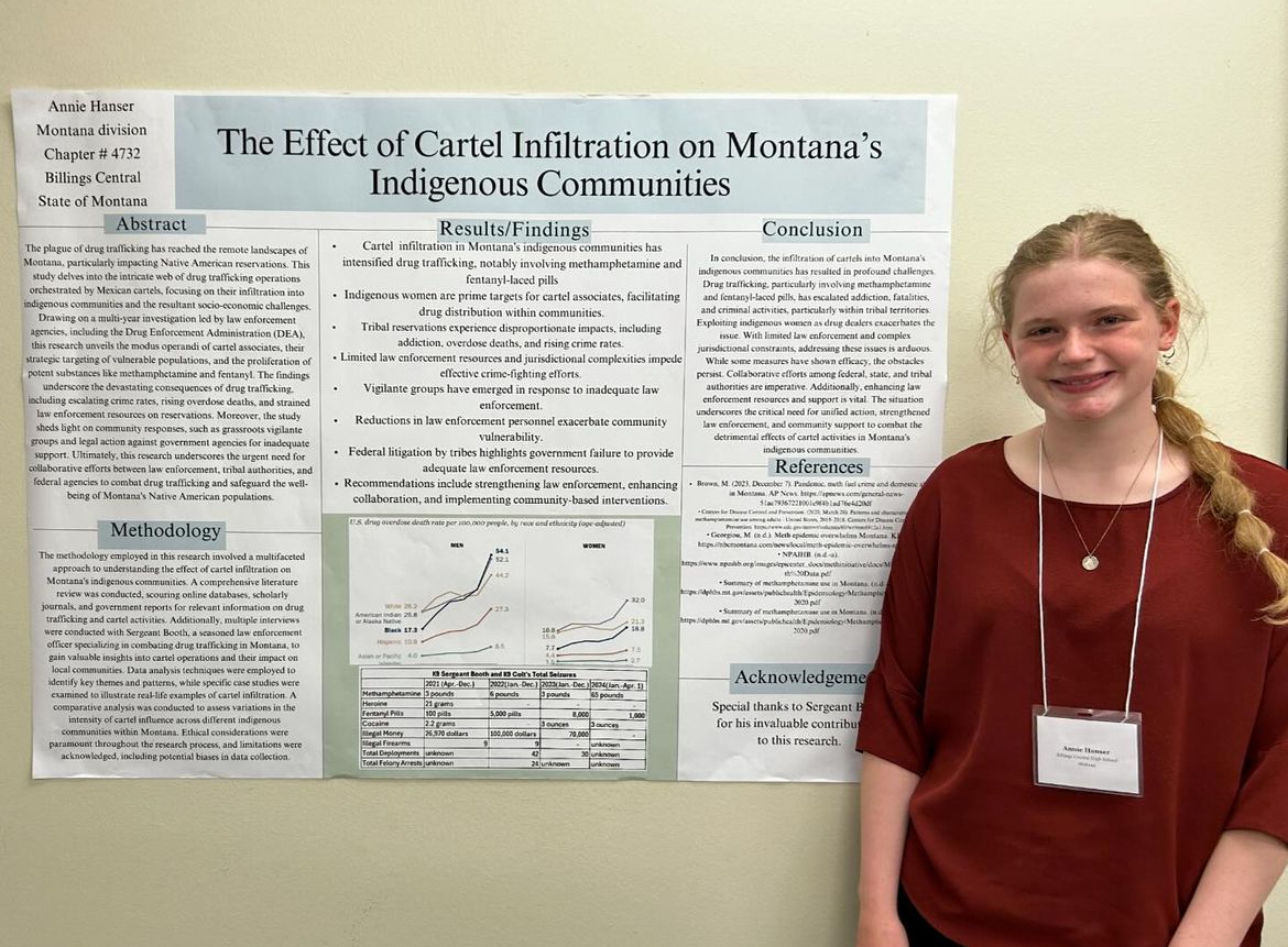 4/3/24 Junior, Annie Hanser with her poster “The Effect of Cartel Infiltration on Montana’s Indigenous  Communities” for her event. 