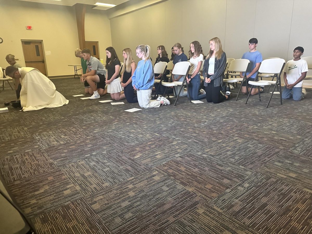 8.24.24: Students kneel as Deacon Nate Haney prepares incense for Benediction. 