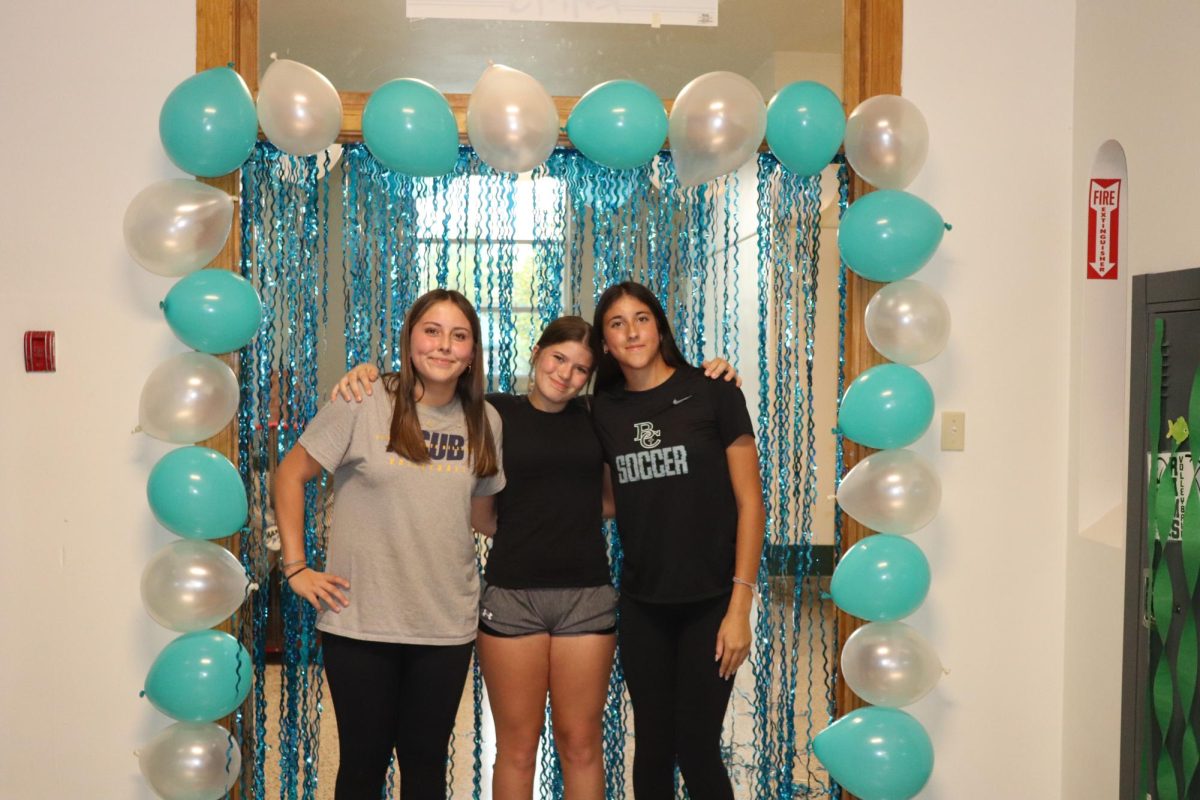 9.8.24 Freshman (L to R) Kenzie Weekly. Chloe Hamilton, and Lorelei Hutzenbiler pose for a photo during hallway decorating for homecoming.