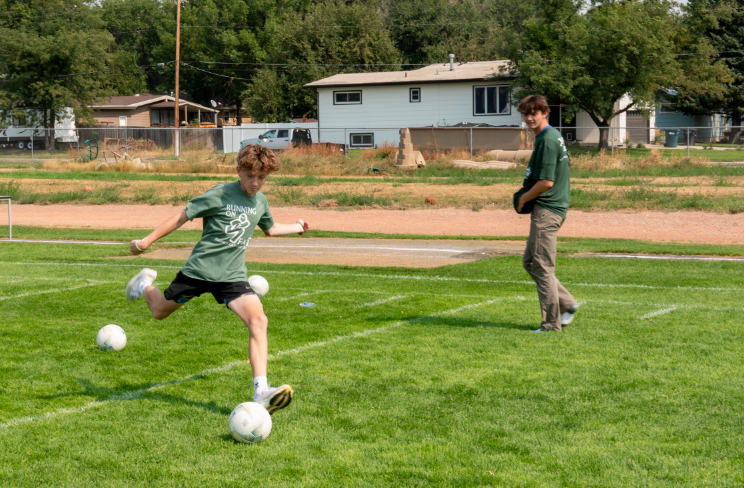 9.8.24 Sophomore Sawyer Guenthner shoots for a goal at the soccer booth at Running on Faith. 