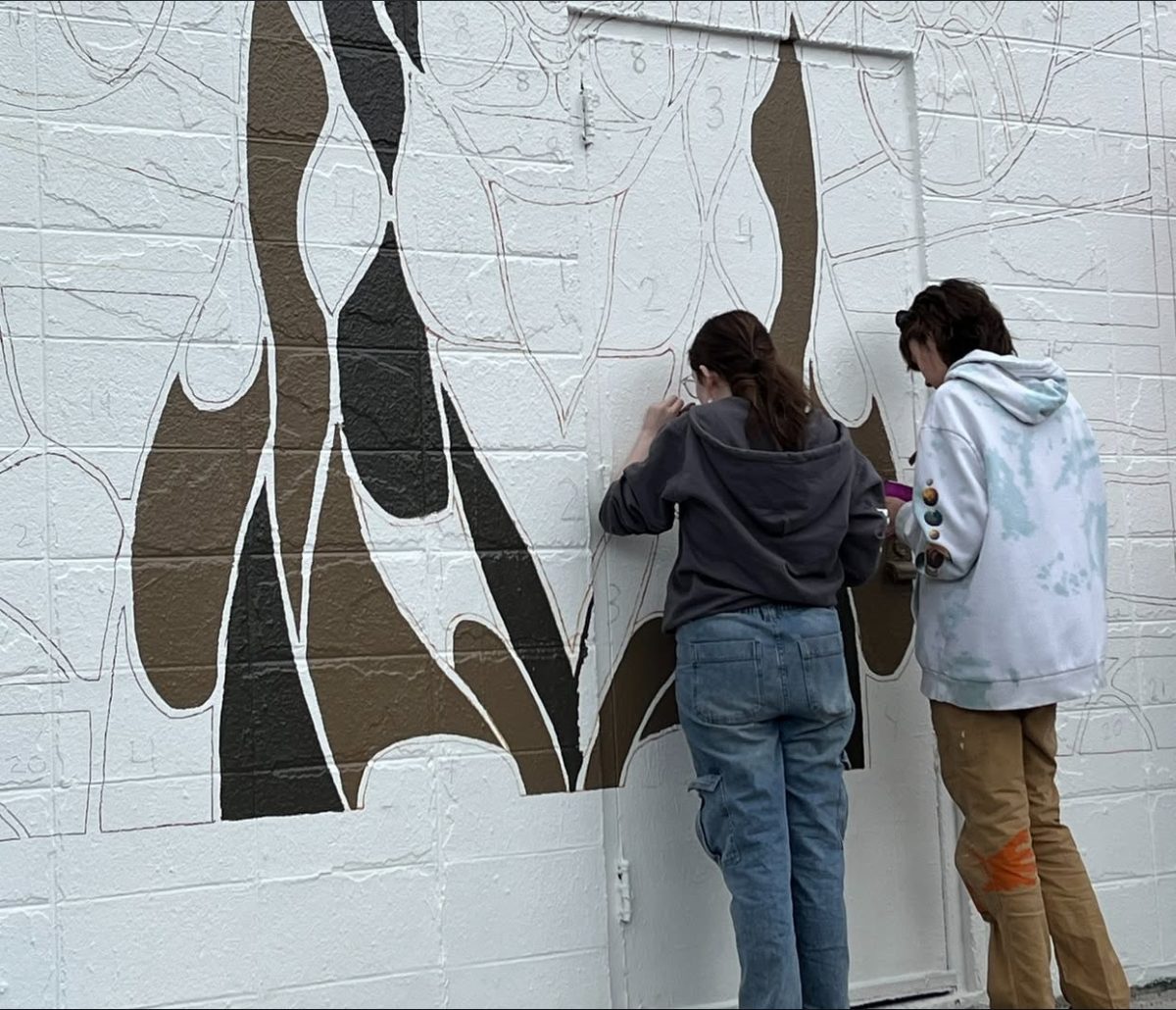(From L to R) Sophomore Vivian Hastings and Junior Kylie Poling working on the Masterlube Mural. 
