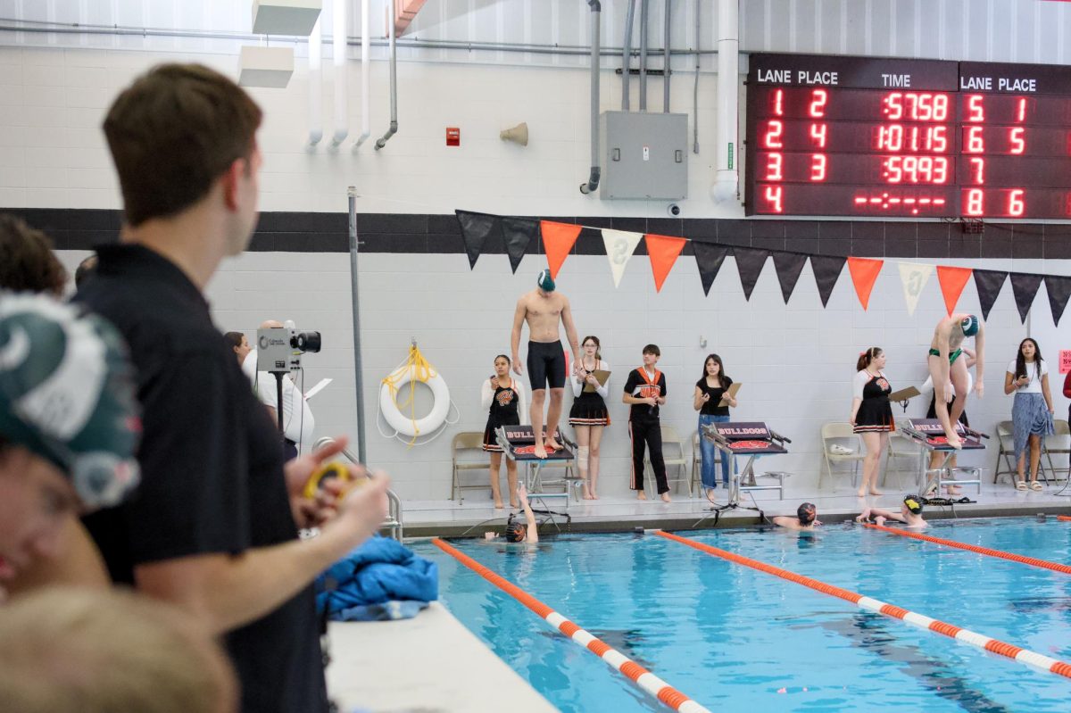 1.9.26 Central swim coach Patryk Seitz watching as two Central swimmers prepare to dive off the blocks.