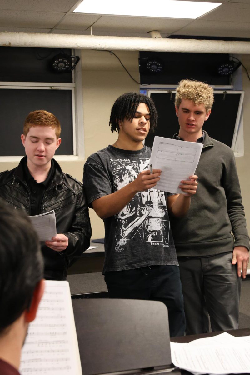 1.15.26 (From L to R) Junior Noah Duncil, senior Evan Cass, and senior Alex Johnson singing while Mr. Martinez plays the piano.